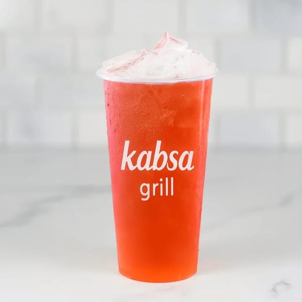 Kabsa Grill's red iced drink with ice cubes on top, against a white tiled background.